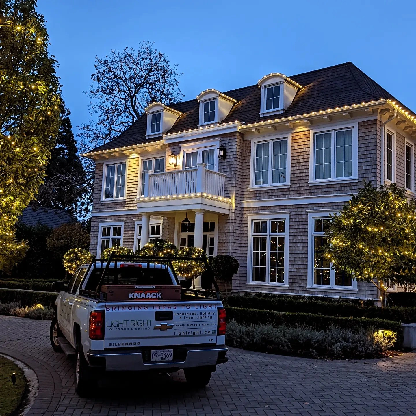 Light Right truck in front of beautiful home lit up by Christmas lights