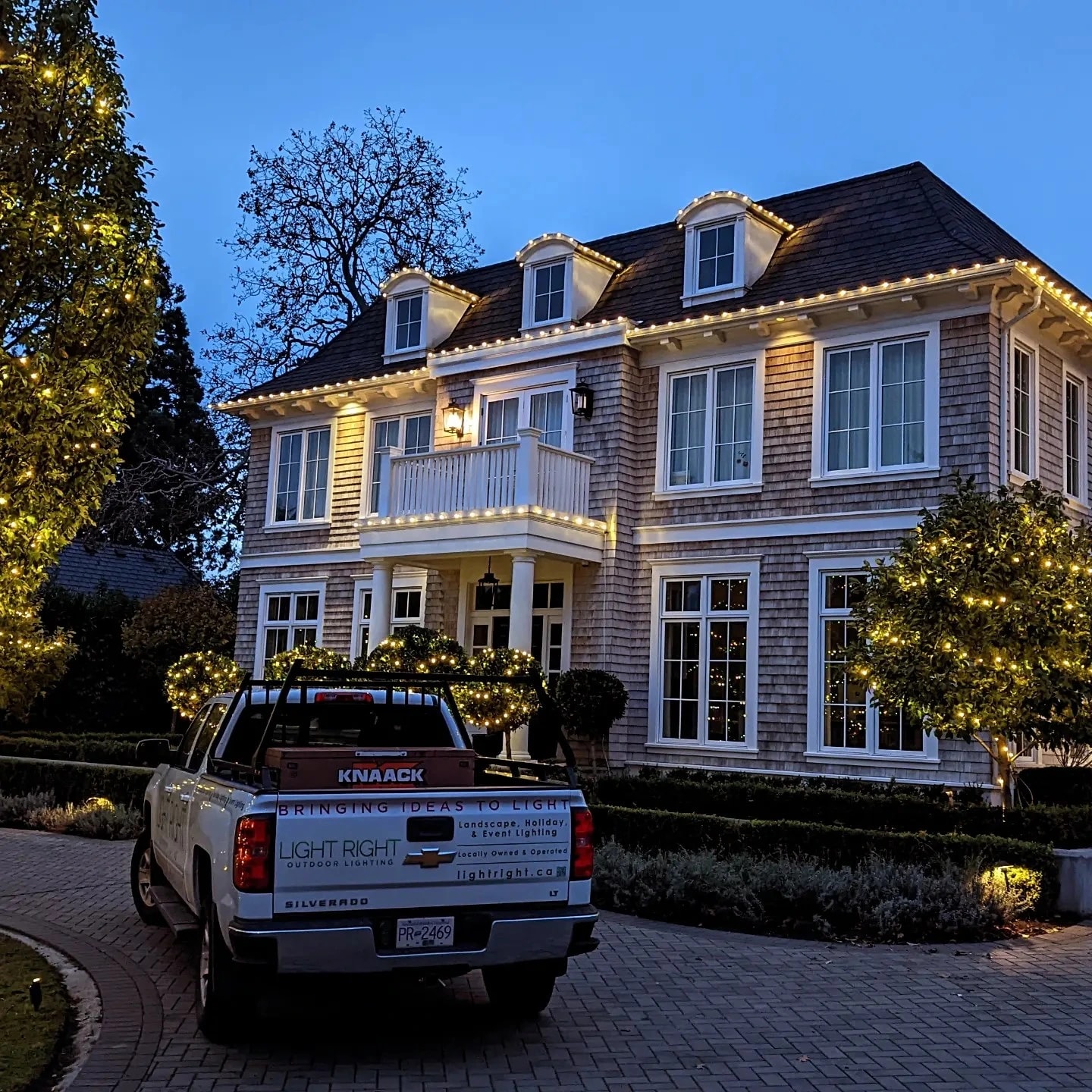 Light Right truck in front of beautiful home lit up by Christmas lights