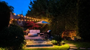 Backyard landscape lighting in Victoria, BC featuring illuminated garden paths, patio steps, trees, and planting beds.